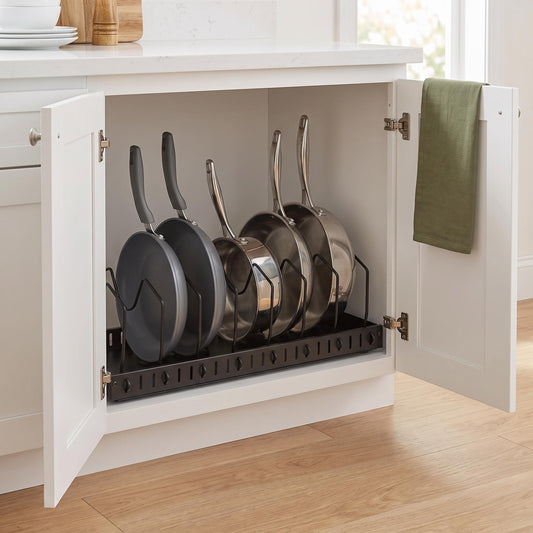 Black metal pot and pan organizer holding five pans upright inside an open kitchen cabinet