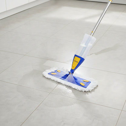 Spray mop releasing fine water mist onto gray tile floor showing wet clean path ahead of pad